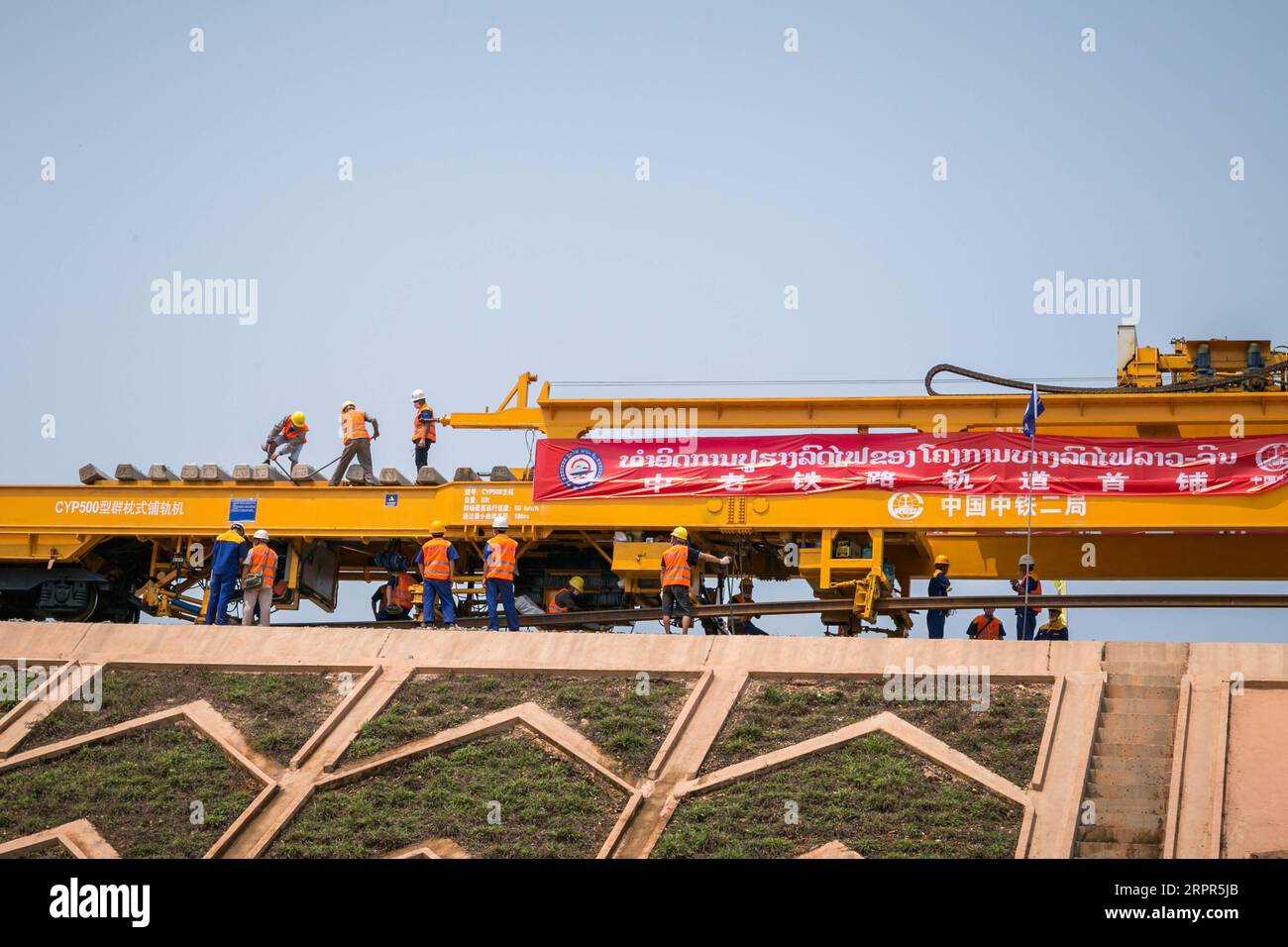 200327 -- VIENTIANE, March 27, 2020 -- Workers lay tracks at the construction site of the China-Laos railway in Vientiane, Laos, March 27, 2020. With its first 500-meter-long rail steadily laid on the subgrade, the China-Laos railway kicked off its track laying work on Friday in Lao capital Vientiane. The rail is the longest one outside China in Asia and it was also the first time the CYP500 track laying machine has been used in railway construction in Southeast Asia, said Hu Bin, project manager of the China Railway No. 2 Engineering Group CREC-2. Photo by Saiyasane/Xinhua LAOS-VIENTIANE-CHIN Stock Photo