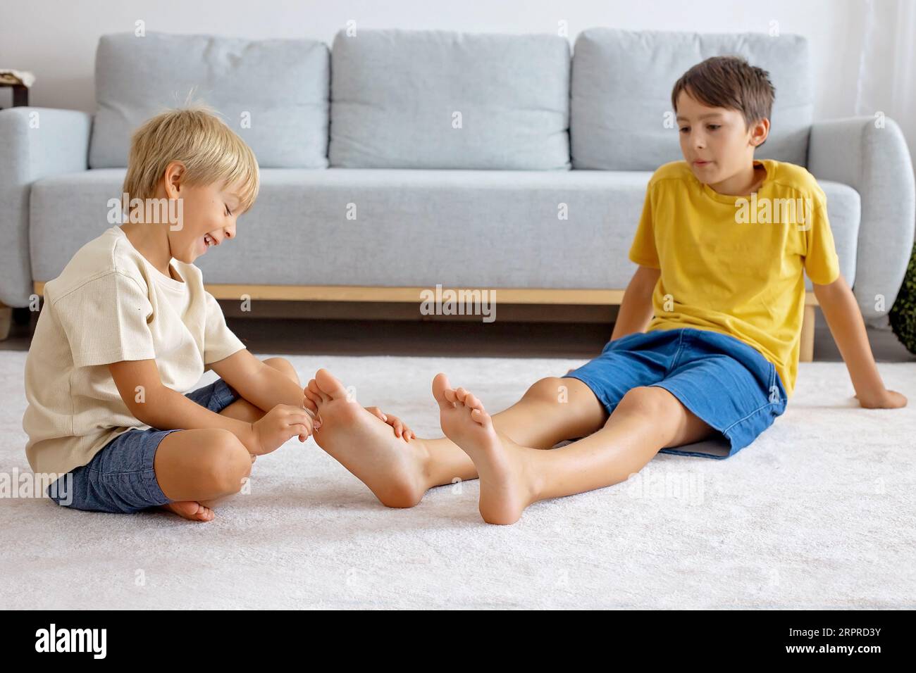 Happy positive children, tickling on the feet, having fun together, boy brothers at home having wonderful day of joy together Stock Photo