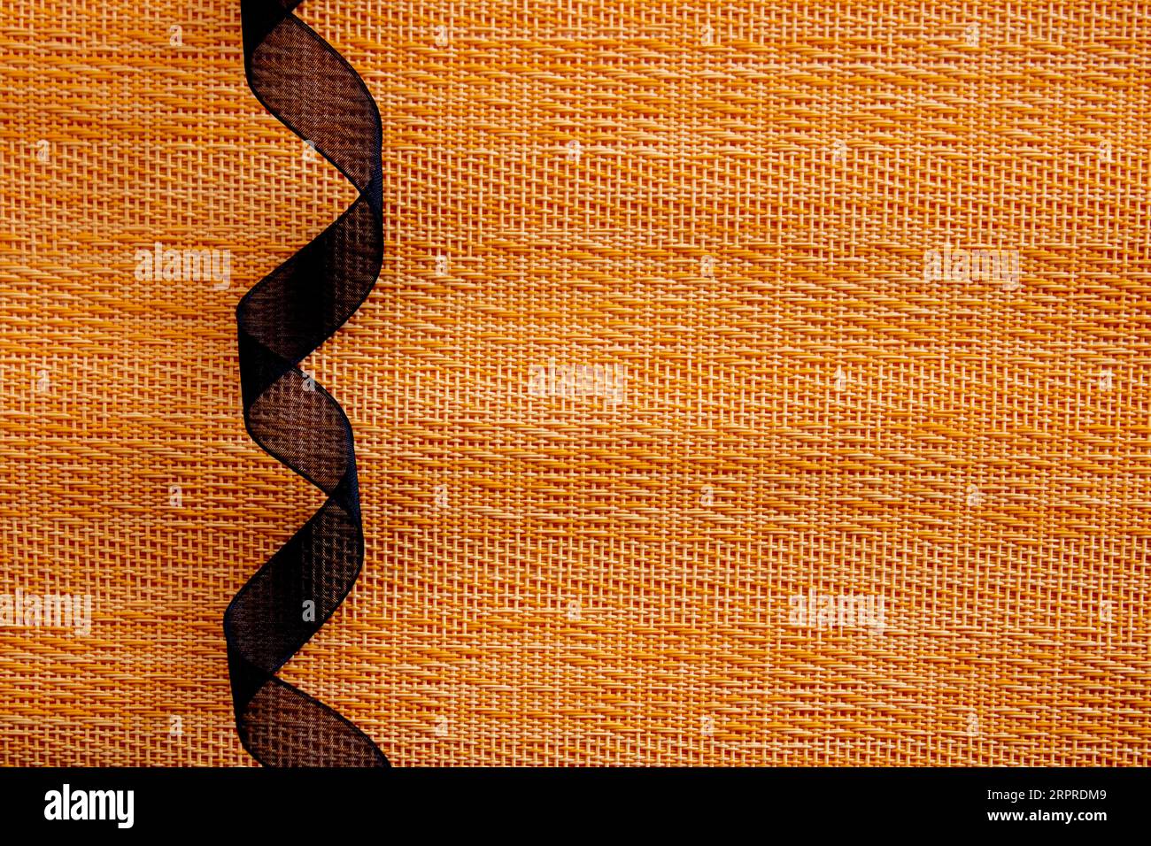 rolled black ribbon on orange textures background. halloween concept Stock Photo
