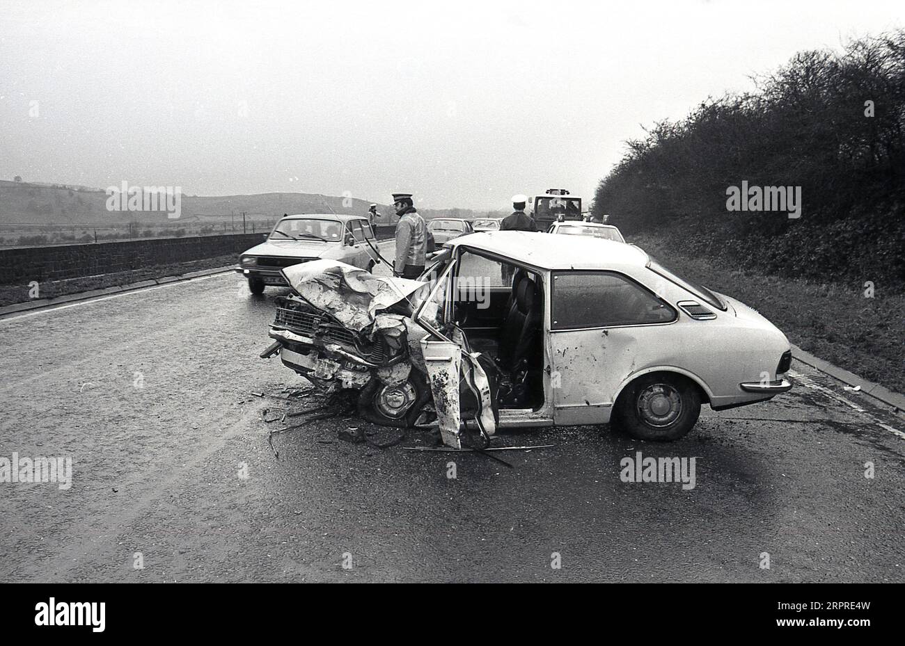 1983, historical, crashed car lying sideways in a road, police administering road traffic, Yorkshire, England, UK. Stock Photo