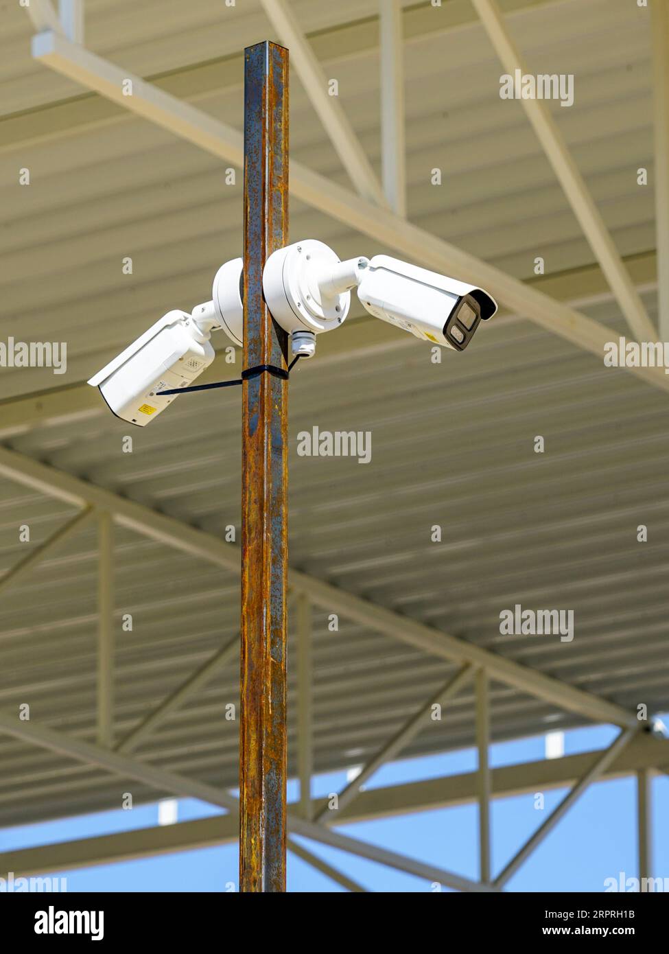 Metal pole with two outdoor security CCTV surveillance cameras in an unfinished building construction site Stock Photo