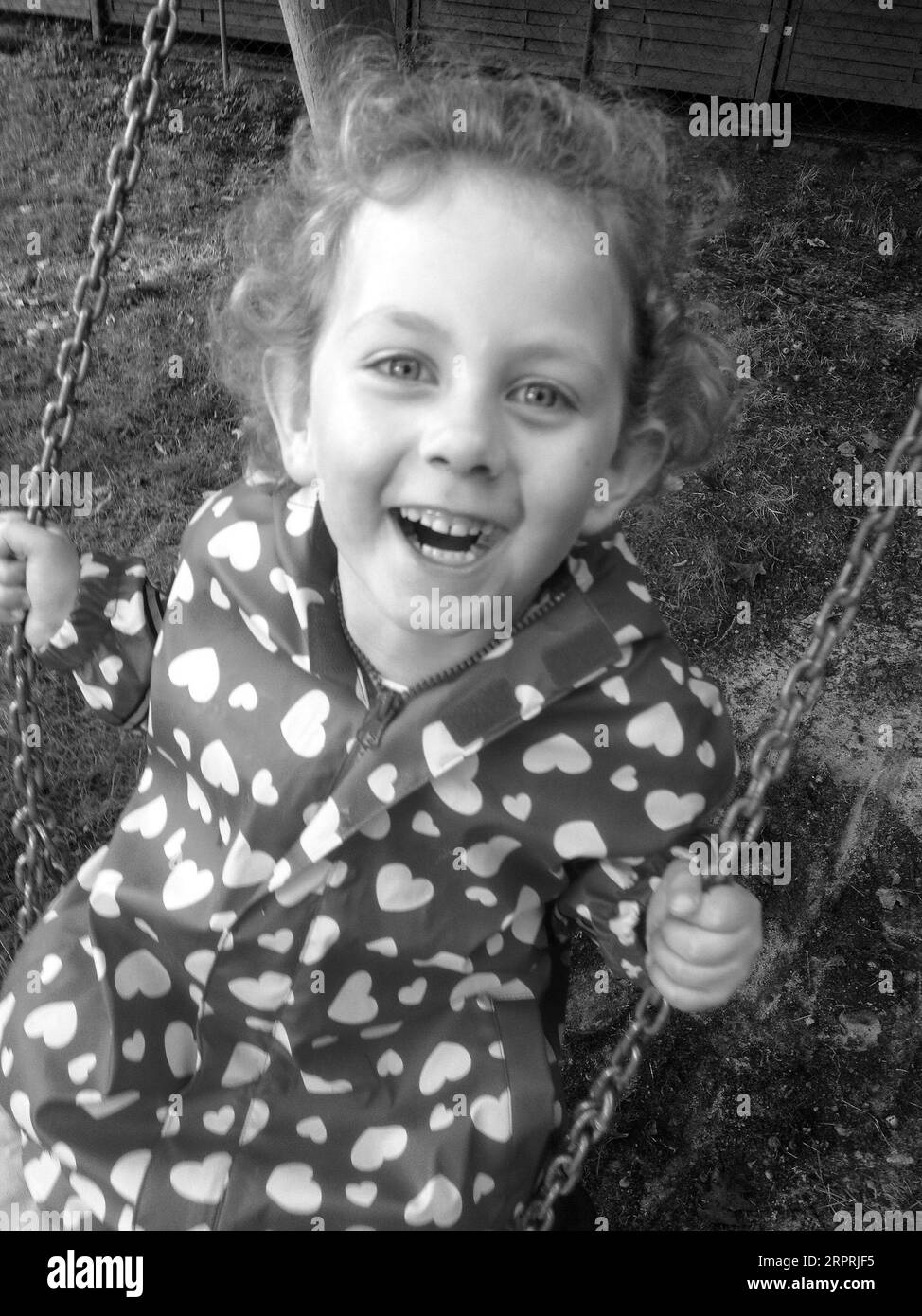 black-and-white-portrait-of-a-5-year-old-blond-girl-on-a-swing-stock