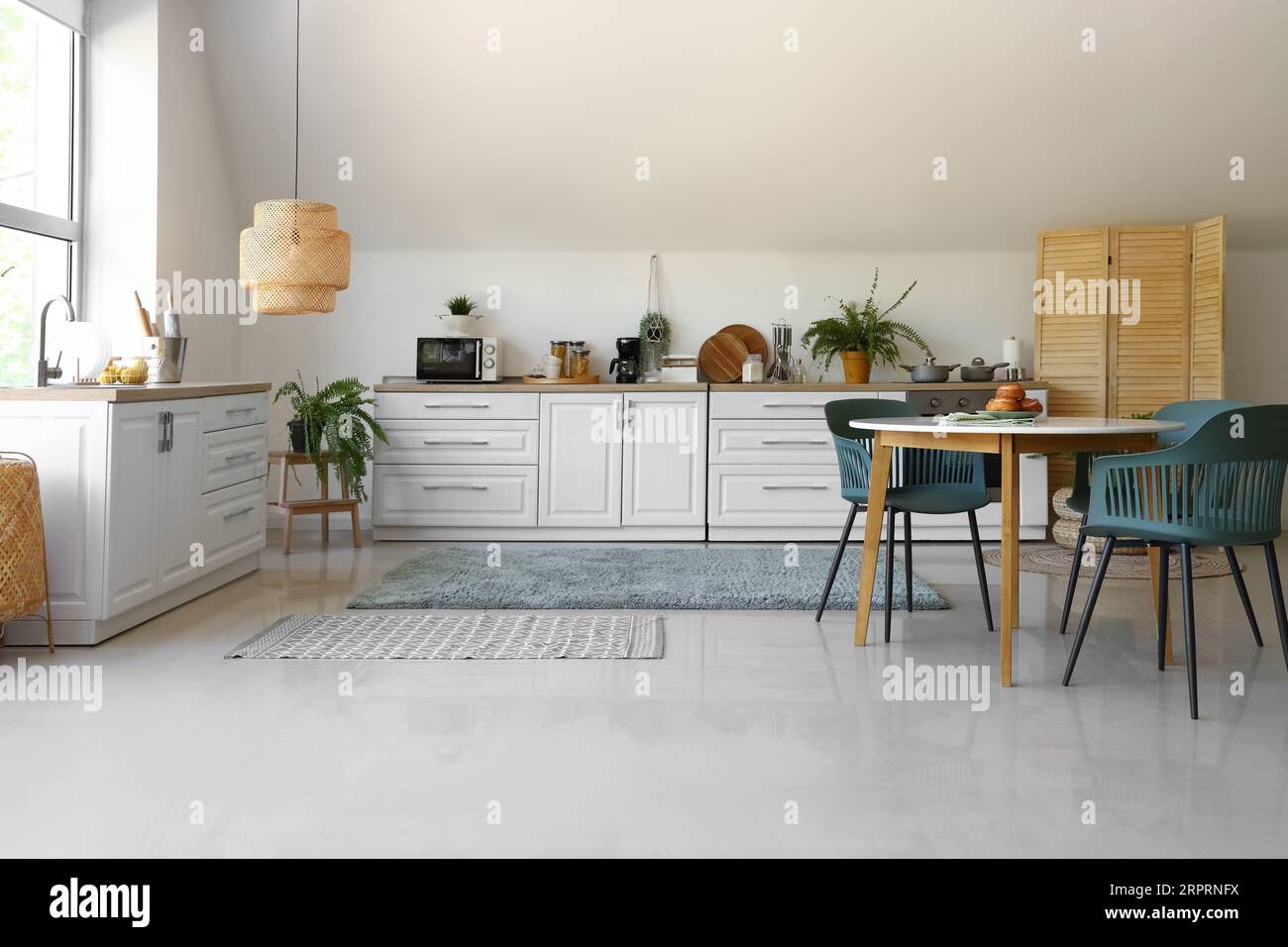 Interior of modern kitchen with white counters and dining table Stock ...