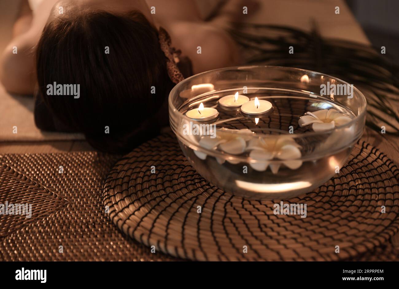 Bowl of water with burning candles and plumeria flowers on table in ...