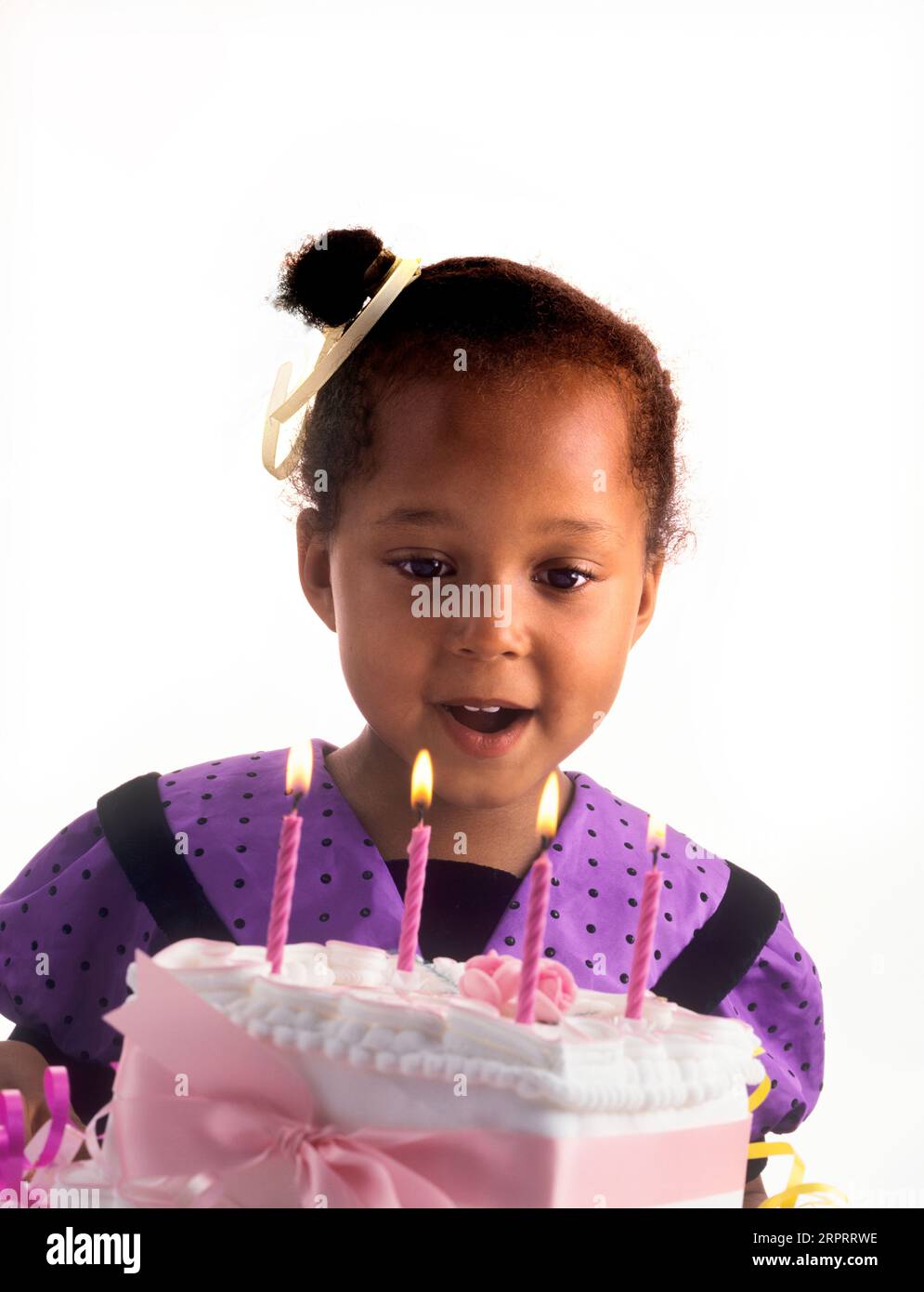 BIRTHDAY INFANT GIRL HAPPY Cake candles 4 years old cute pretty British African Afro Caribbean girl celebrating with her special birthday cake making Stock Photo
