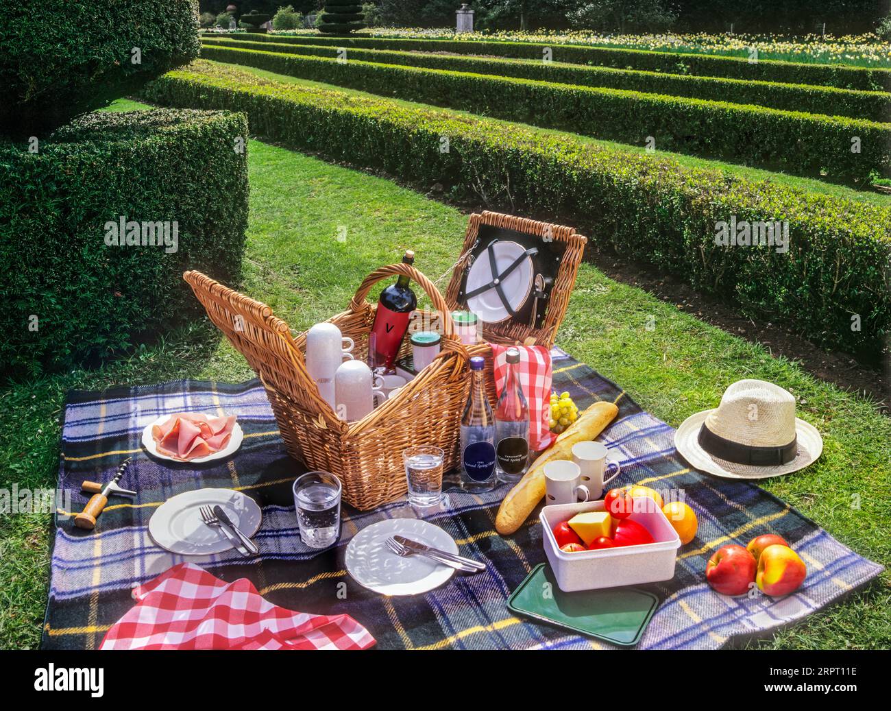 Picnic basket hamper and formal alfresco UK garden, food & wine selection laid out in a summer British English stately home country estate, England UK Stock Photo