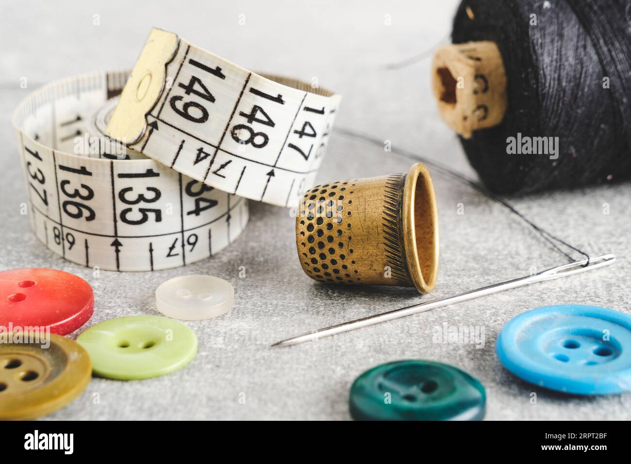 Sewing kit of needle, thimble, thread and measuring meter.On gray ...