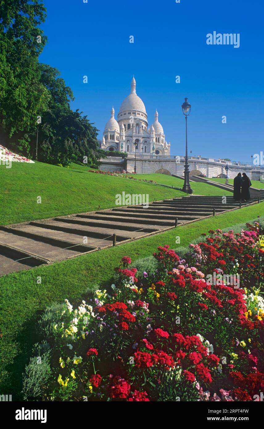 Sacre Coeur Montmartre Paris with spring bedding geraniums. Two Nuns  on steps for morning prayer. The Basilica Sacred Heart Montmartre Paris France Stock Photo