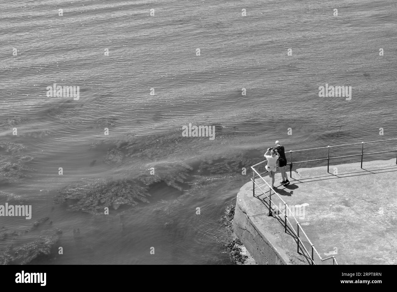 A couple look out to sea from the quayside. There is a great deal of