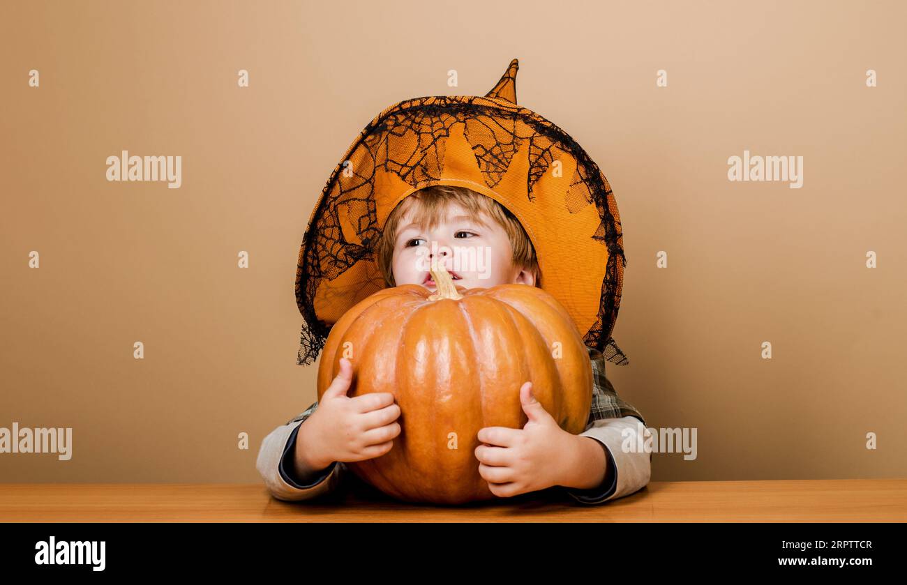 Autumn recipes. Cute child in witch hat with big pumpkin for Thanksgiving day cooking or Halloween preparation. Ingredients for pumpkin pie for Stock Photo