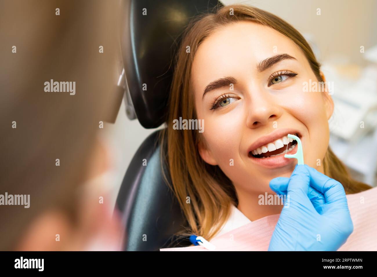 Young beautiful woman in the dentist office, listening to the doctor how to use dental floss