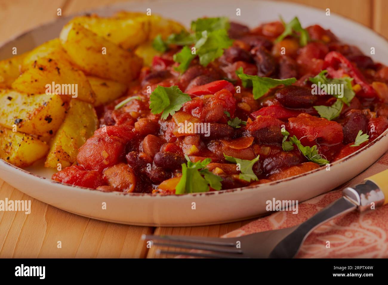 Spicy chicken chilli with oven baked potato wedges. Stock Photo