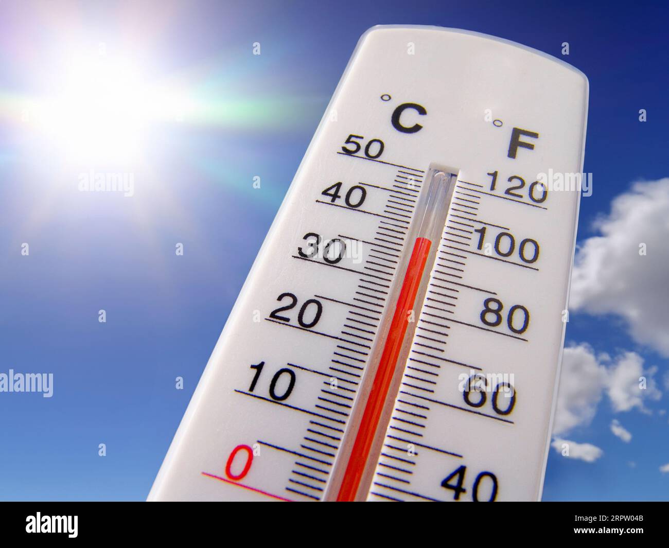 Thermometer sunburst 38C HEATWAVE HOT 100F Temperature gauge rising red Concept Sky Thermometer displays hot & sunny 38C centigrade 100F degrees farenheit against a bright blue sky Climate change Global warming concept Stock Photo