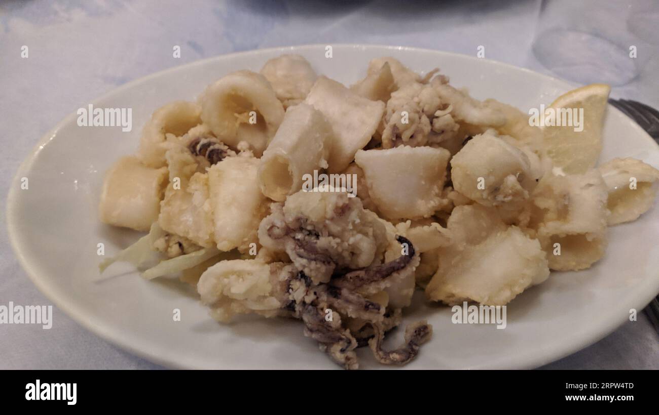 Fried squid rings breaded calamari appetizer set on cast iron frying