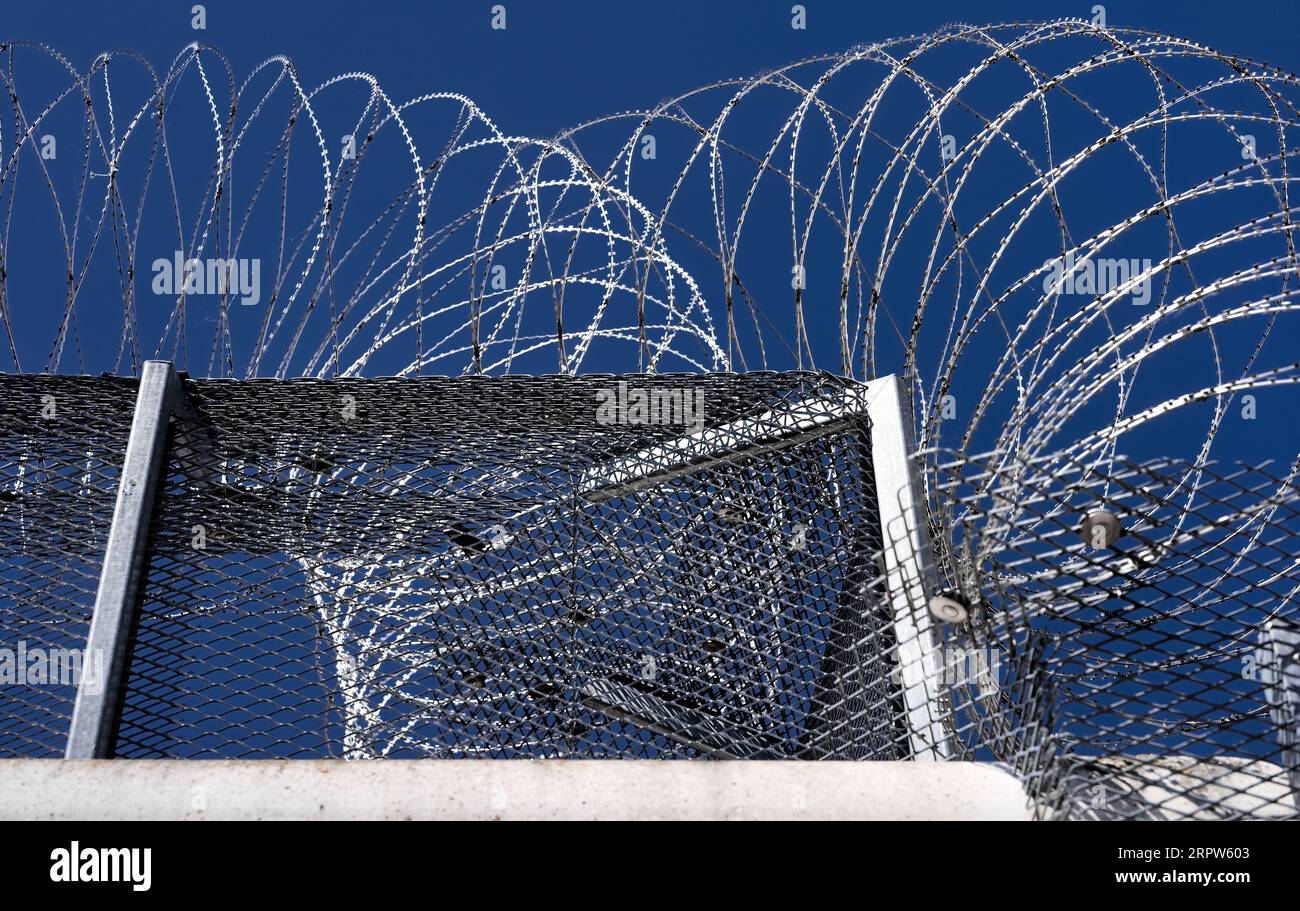 Wall with razor barb wire tape fencing property enclosure perimeter