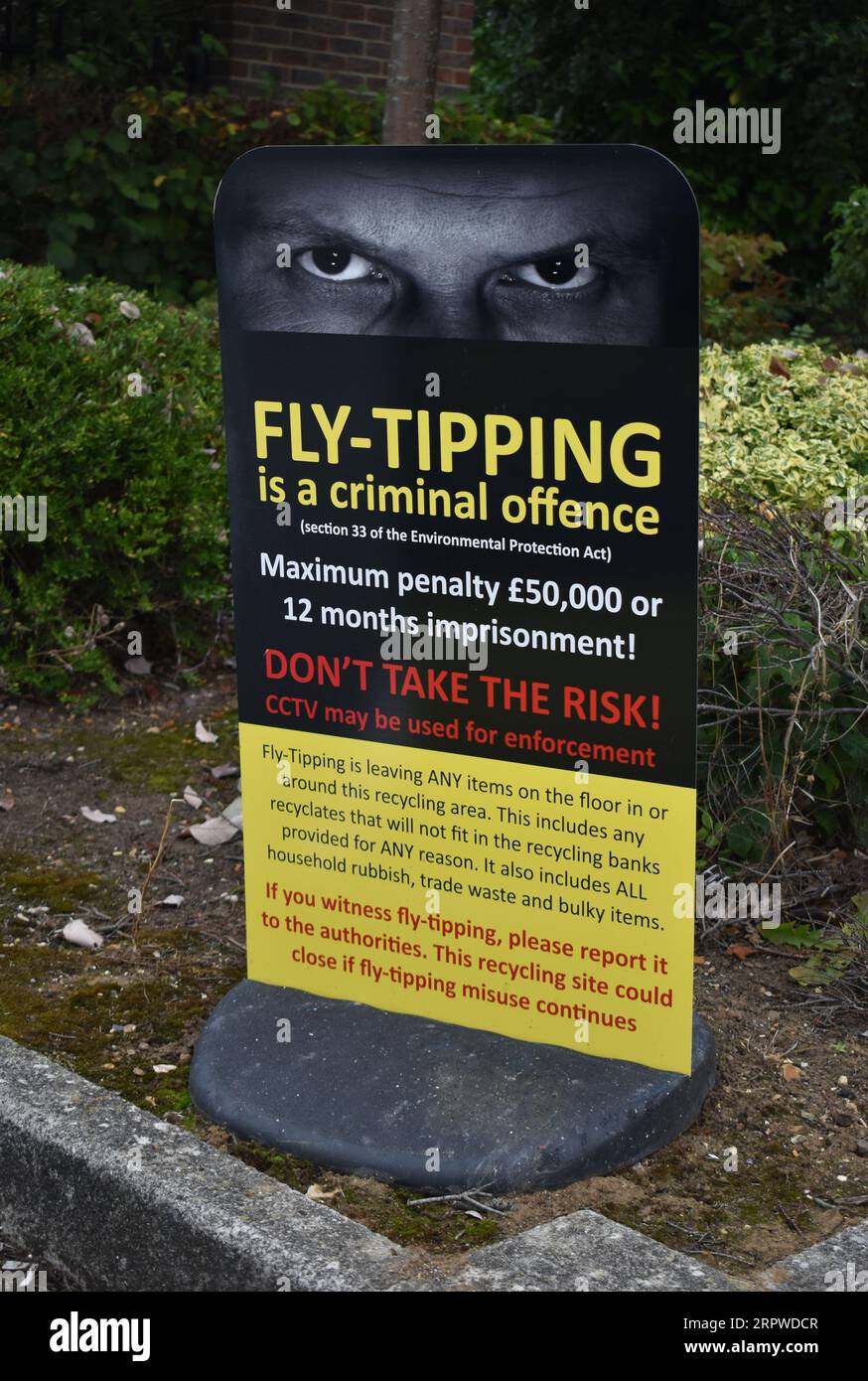 A notice about fly-tipping beside some clothing recycling banks. Stock Photo