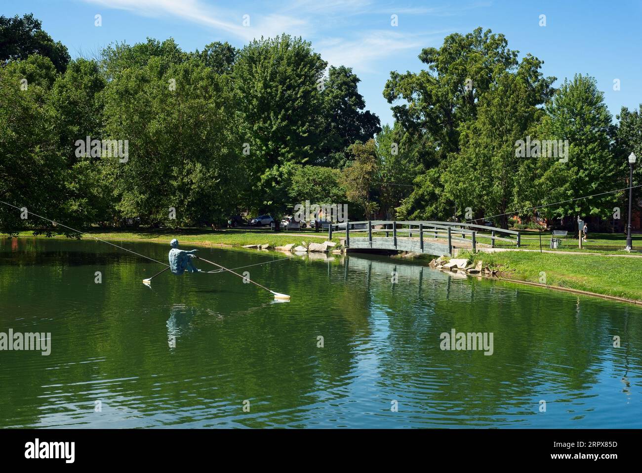 A sculpture of a rower is suspended above a pond in Schiller Park in