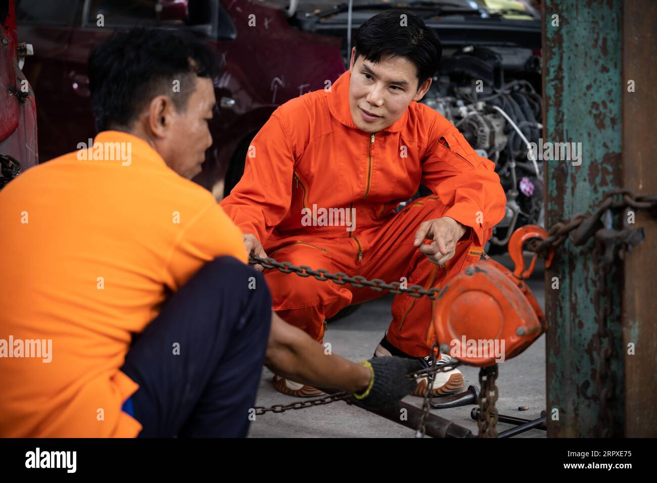 Mechanic testing strength and reliability of chain hoist for car towing
