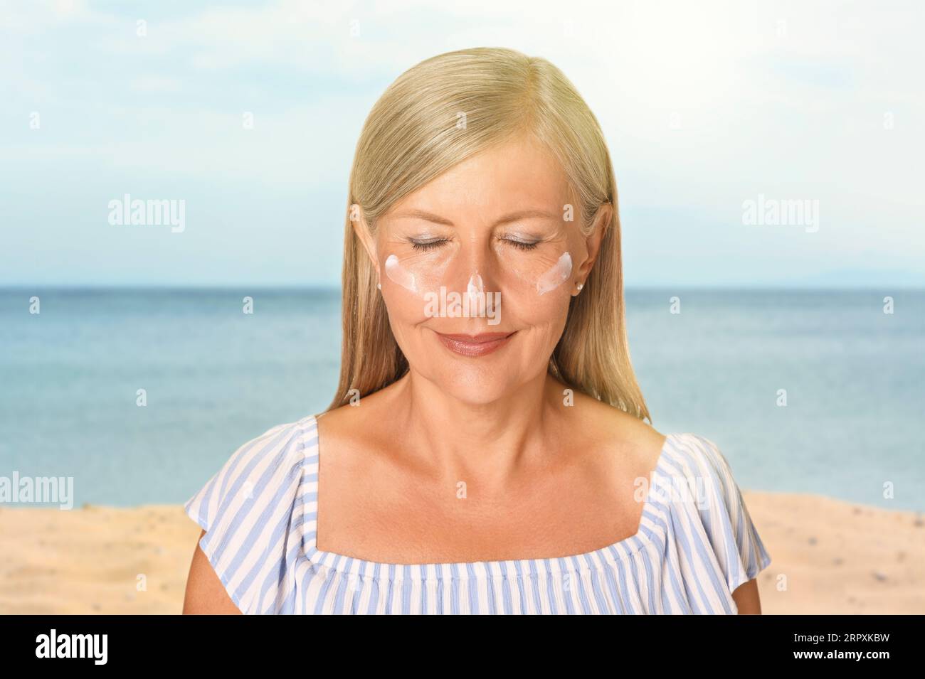 Sun protection. Beautiful young woman with sunblock on her face near sea Stock Photo