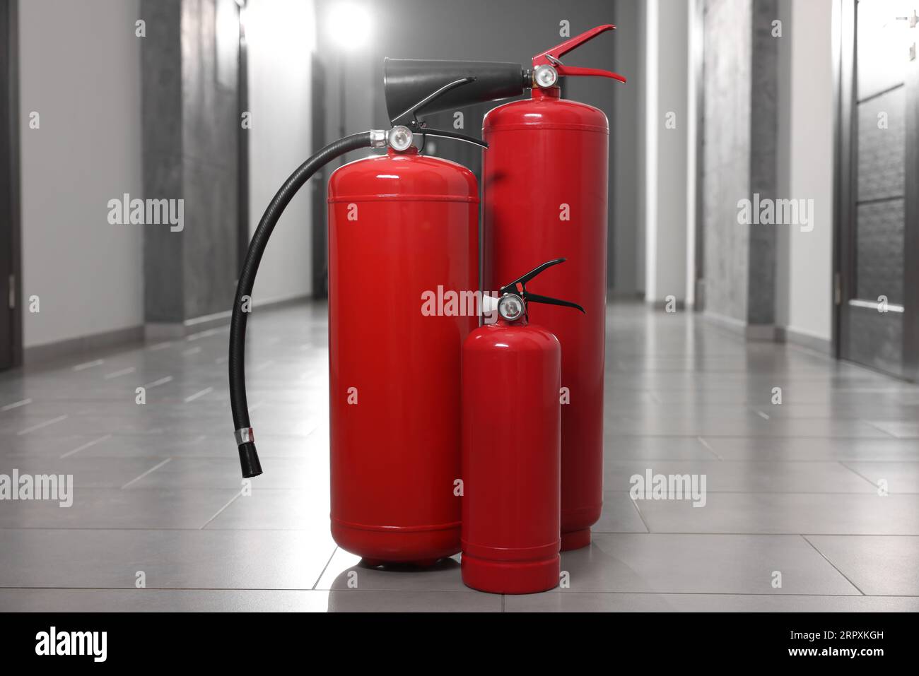 Three new red fire extinguishers in hall Stock Photo Alamy