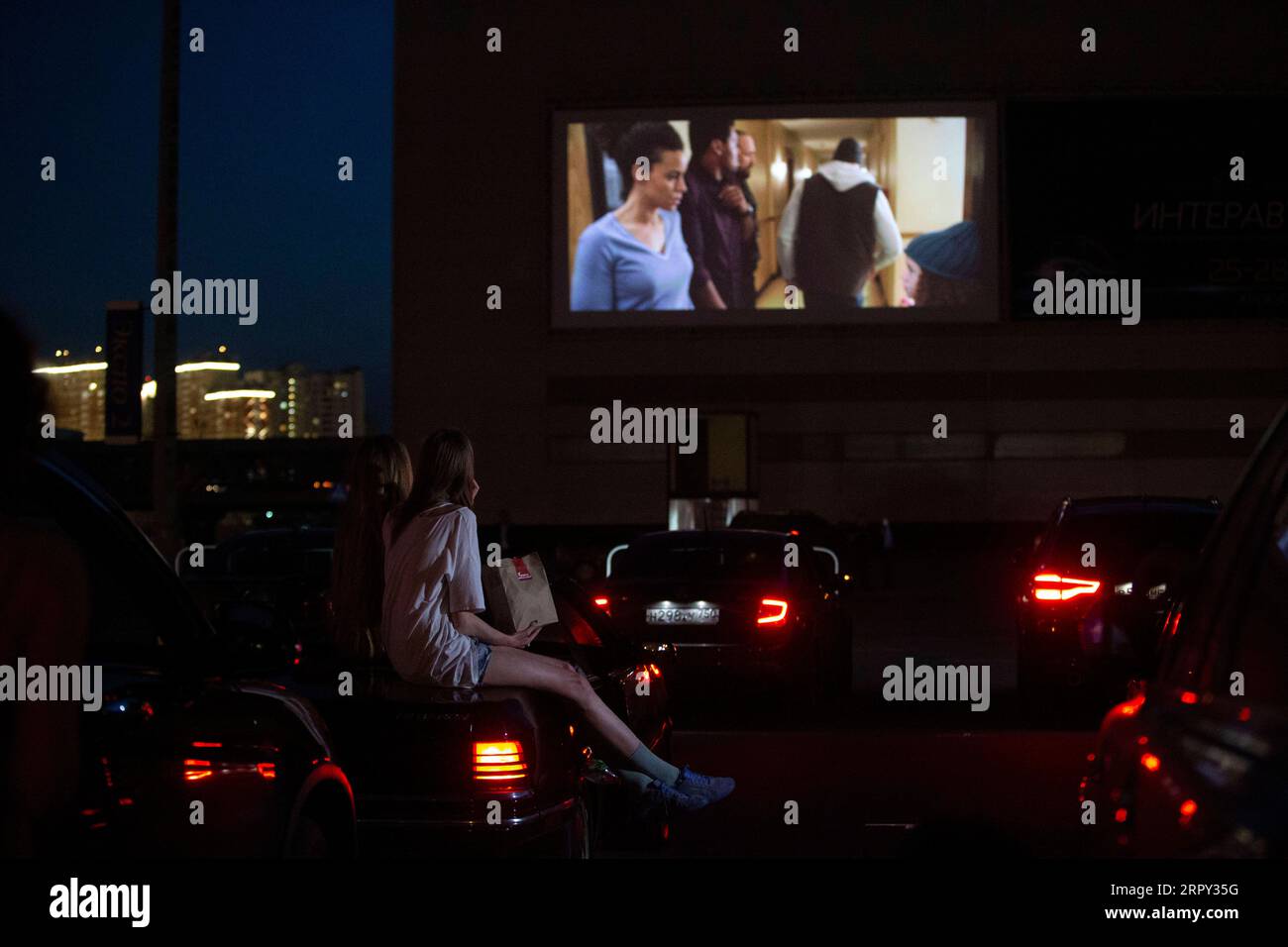 200612 -- MOSCOW, June 12, 2020 Xinhua -- Girls sit on their car watching a movie at a new drive-in cinema at a mall outside Moscow, Russia, on June 11, 2020. Photo by Alexander Zemlianichenko Jr/Xinhua RUSSIA-MOSCOW-DRIVE-IN CINEMA PUBLICATIONxNOTxINxCHN Stock Photo