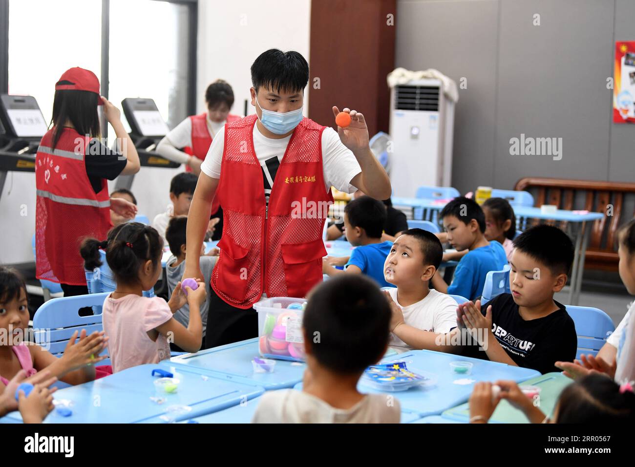 200729 -- HEFEI, July 29, 2020 -- A volunteer plays games with children at a temporary shelter in the No.168 Middle School in Hefei, east China s Anhui Province, July 29, 2020. Affected by floods, more than 300 villagers in Sanhe Town of Hefei were transferred to the school. Free meals, psychological counseling and daily living assistance are provided in the shelter.  CHINA-ANHUI-HEFEI-FLOOD-TEMPORARY SHELTER CN LiuxJunxi PUBLICATIONxNOTxINxCHN Stock Photo