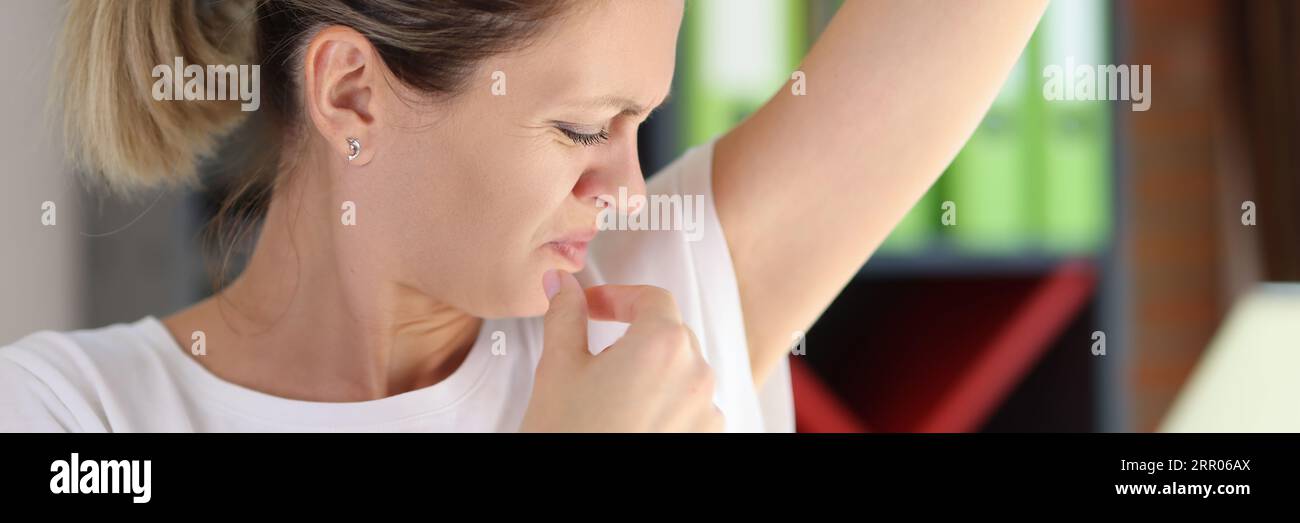 Young female sniffing armpits and feeling of revulsion because of smell Stock Photo