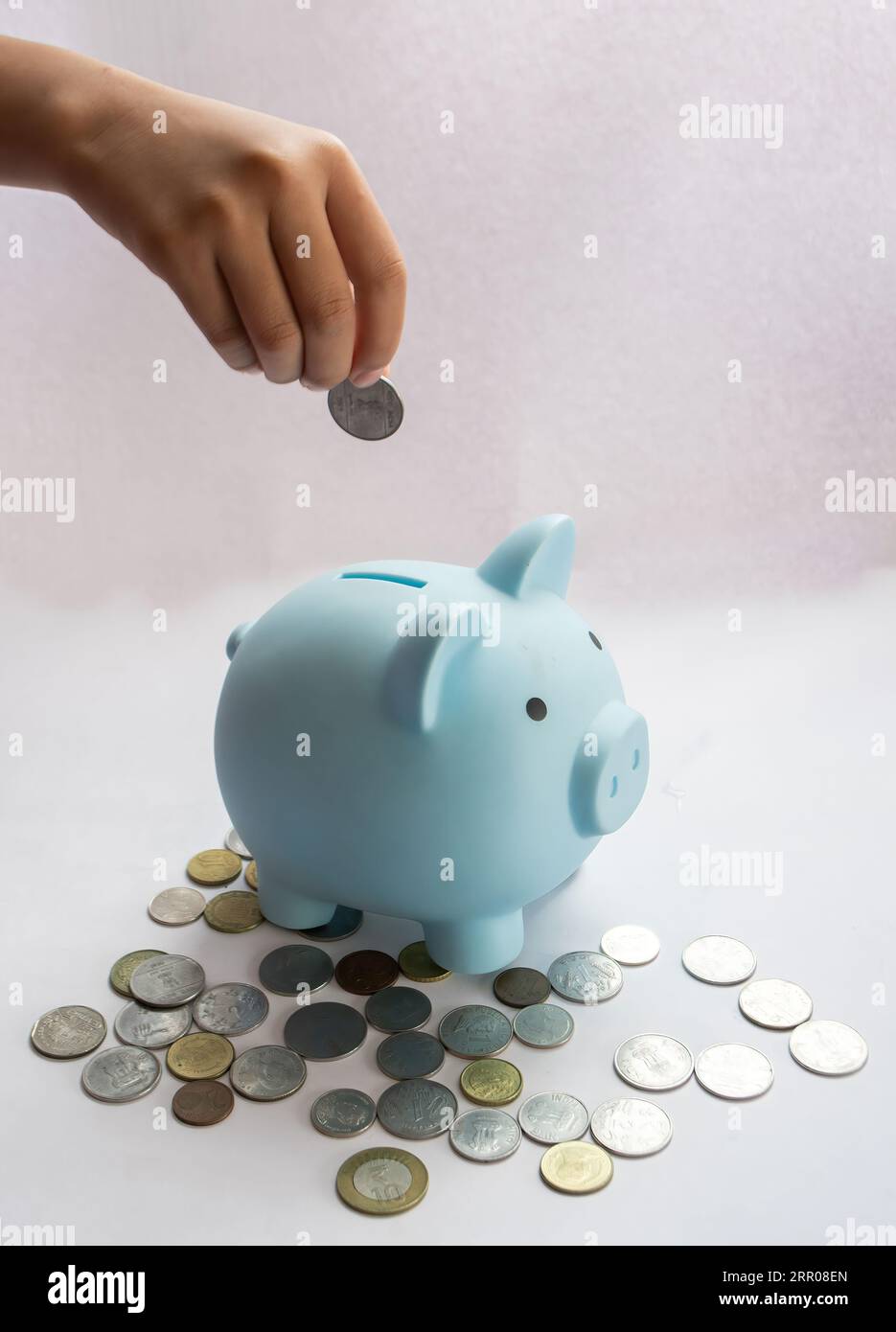 Hand inserting coin in the piggy bank Stock Photo