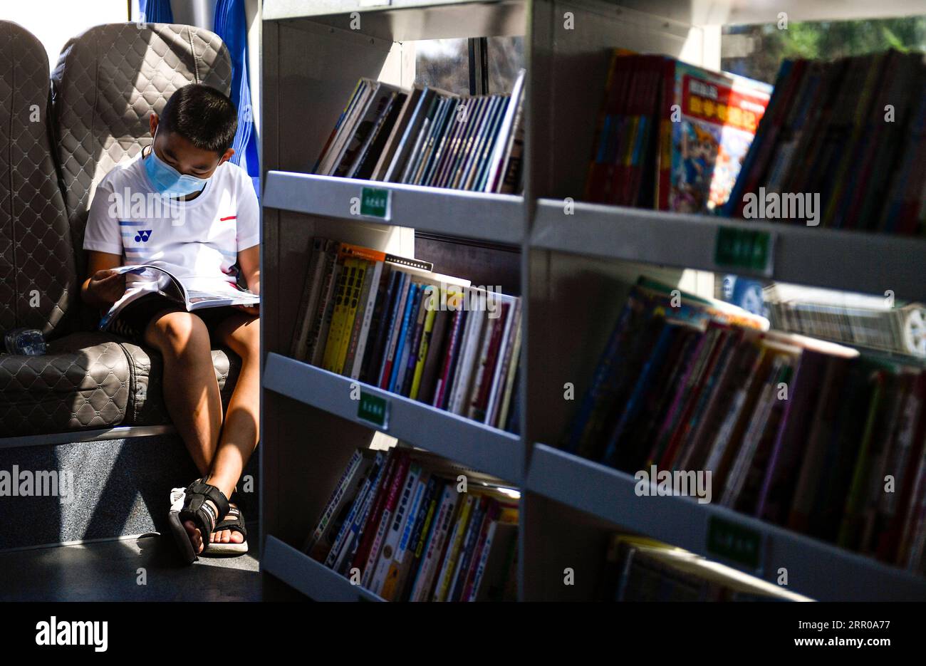 200805 -- CHANGCHUN, Aug. 5, 2020 -- A boy reads a book at a mobile library transformed from a bus in Changchun, northeast China s Jilin Province, Aug. 5, 2020. Changchun Library converted a bus into a mobile library which circulates at 15 fixed service points to provide citizens with book lending service.  CHINA-JILIN-MOBILE LIBRARY SERVICECN XuxChang PUBLICATIONxNOTxINxCHN Stock Photo