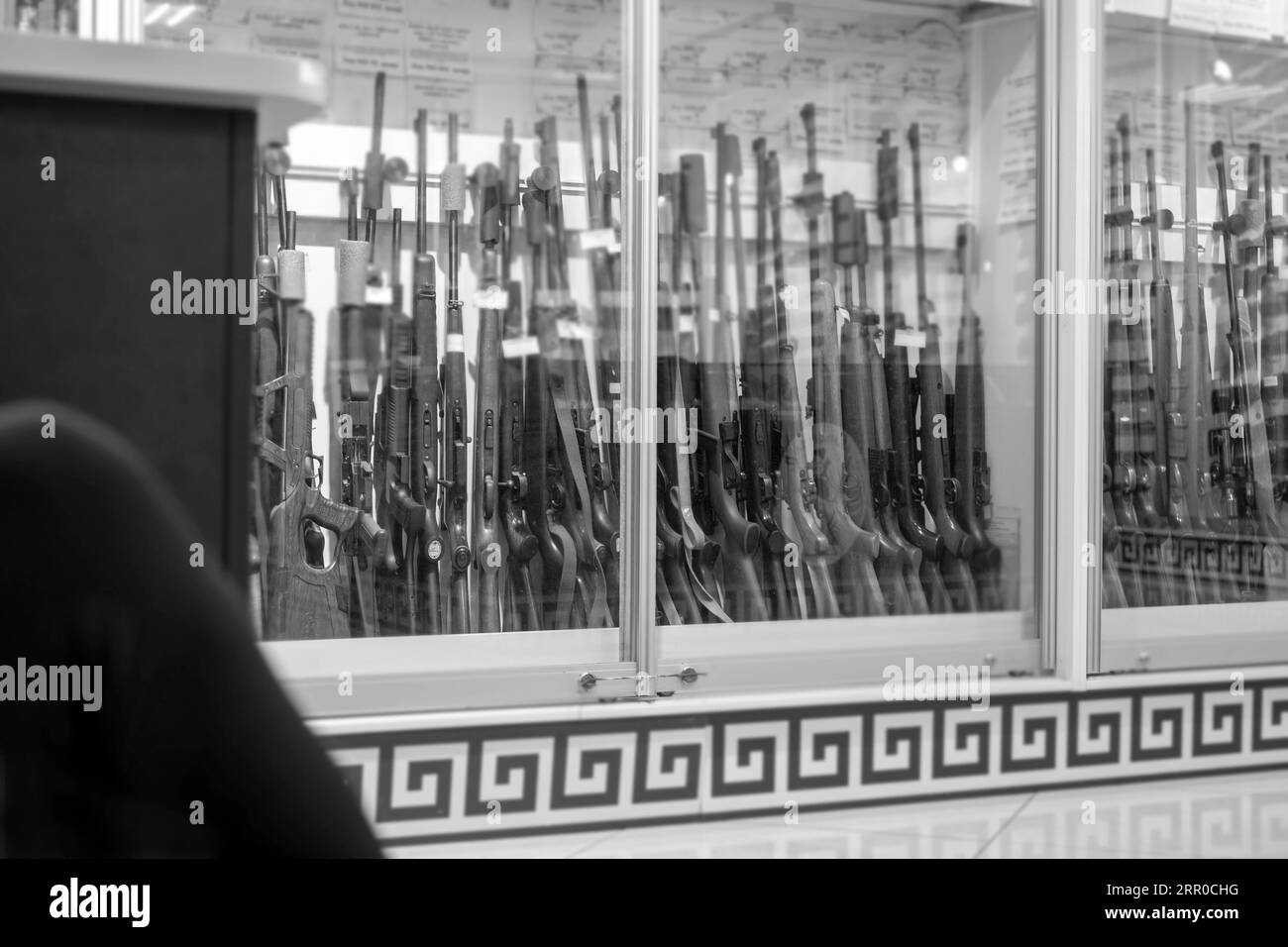 display of a gun shop with rifles behind the bulletproof glass, in