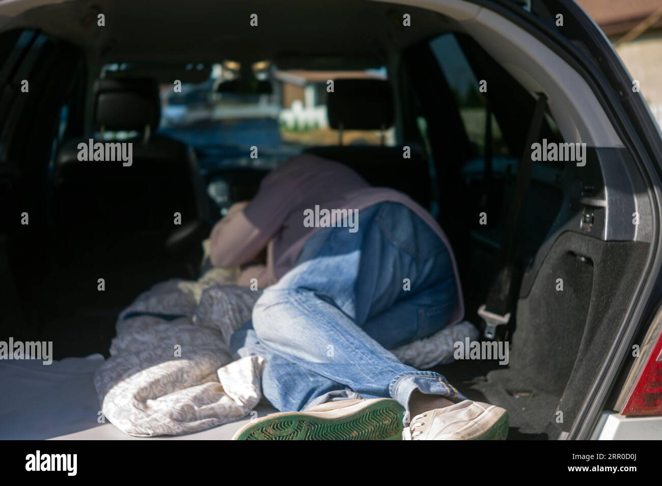 a man sleeping in a car trunk, concept of a break while driving Stock