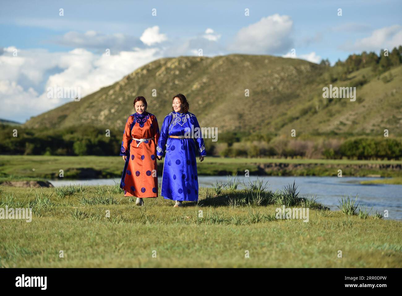 200810 -- HULUN BUIR, Aug. 10, 2020 -- Aijim L and her mother Uran walk along a river in Ewenki Autonomous Banner, north China s Inner Mongolia Autonomous Region, Aug. 6, 2020. Aijim is a post-90s girl of Ewenki ethnic group living in Inner Mongolia Autonomous Region. In 2014, she returned to her hometown at Ewenki Autonomous Banner, Hulun Buir City, after graduation from university, and helped her mother Uran run a handicraft studio. They make handicrafts themed on Sun Flower , and opened up online business to sell the products. Behind the handicrafts we made is the folk story of Sun Girl who Stock Photo