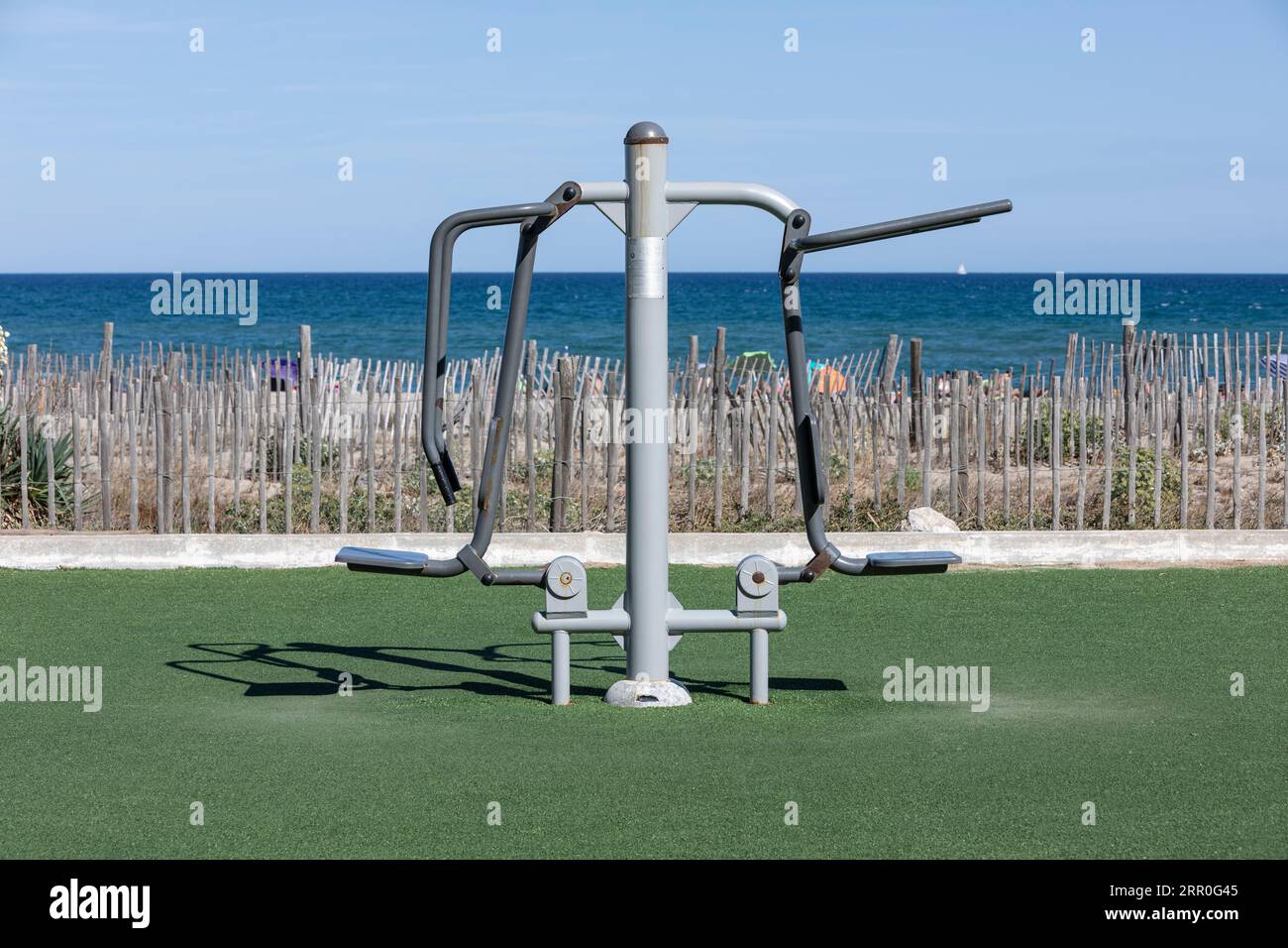 An exercise machine on artficial grass by a Mediterranean beach Stock Photo