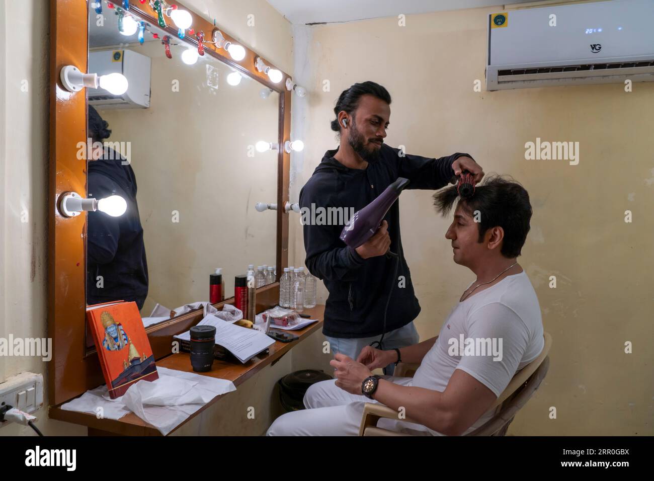 A hairdresser hairstyles an actor at a movie set in Goregaon Film City