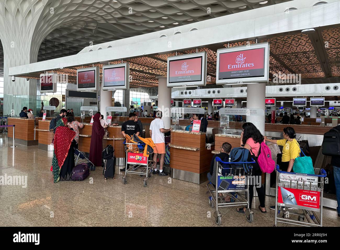 Passengers wait in line to checkin at the counter of Emirates airlines