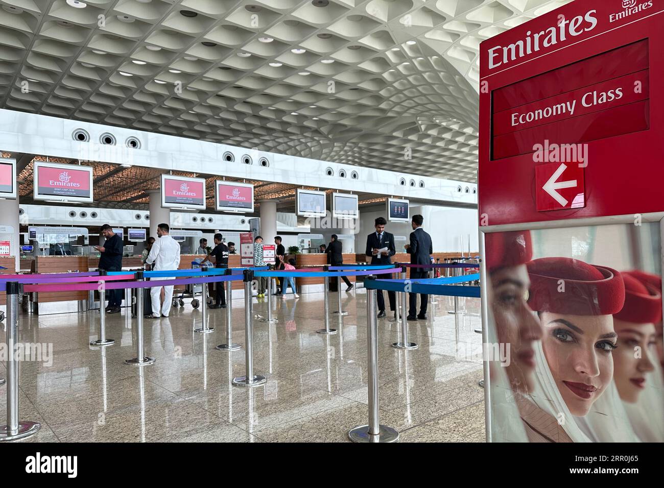 Passengers wait in line to checkin at the counter of Emirates airlines