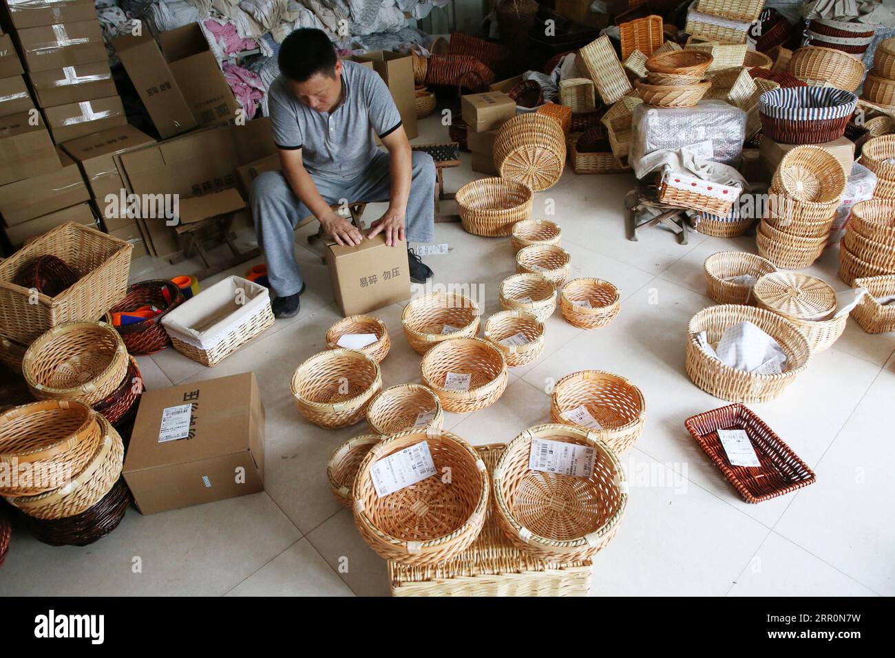 200821 -- TANCHENG, Aug. 21, 2020 -- A merchant packs willow knitting products for domestic sales at an e-commerce industrial park in Miaoshan Town of Tancheng County, east China s Shandong Province, Aug. 20, 2020. Tancheng County has a long tradition of making willow knitting products and encourages craftspeople to pass down old techniques as well as innovate some new ones. By virtue of e-business platform, the willow knitting products are welcomed by domestic and foreign market. Photo by /Xinhua CHINA-SHANDONG-TANCHENG-WILLOW KNITTING PRODUCTS-E-BUSINESS PLATFORM PROMOTION CN ZhangxChunlei P Stock Photo