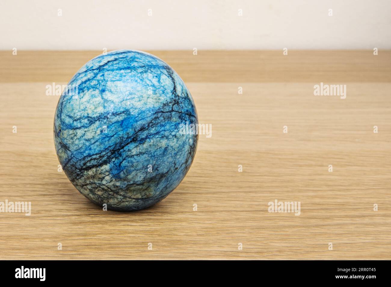 A decorative blue stone ball on an oak wood surface Stock Photo