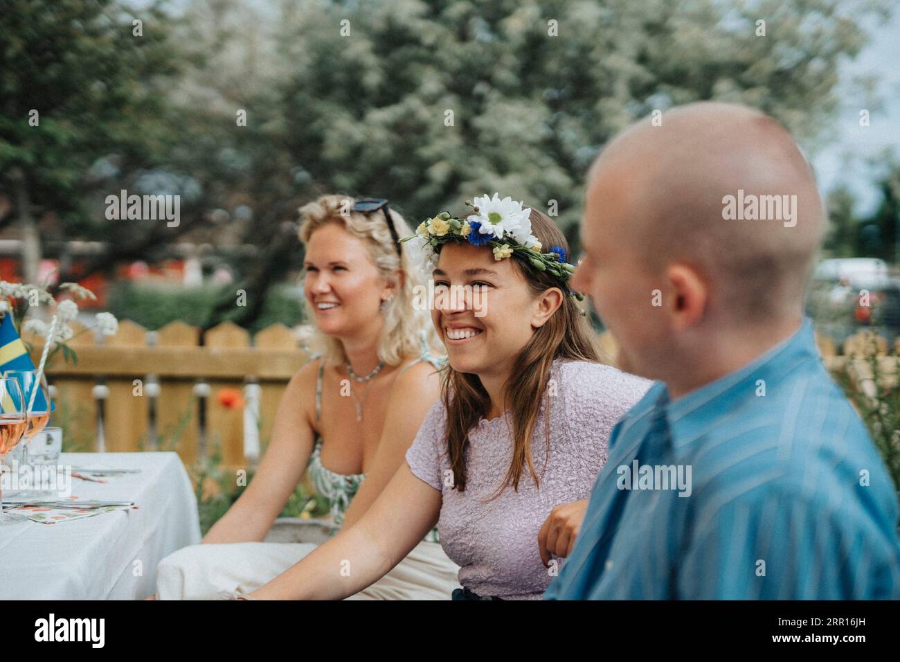 Smiling young woman wearing tiara while enjoying with friends during dinner party at cafe Stock Photo