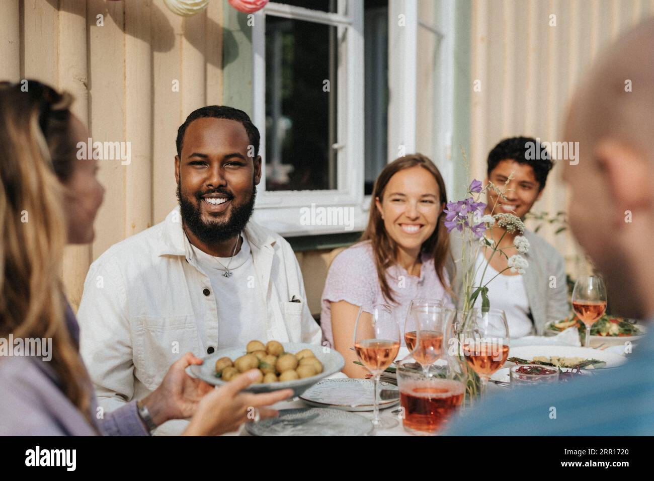Woman serving baby potatoes to male and female friends during dinner