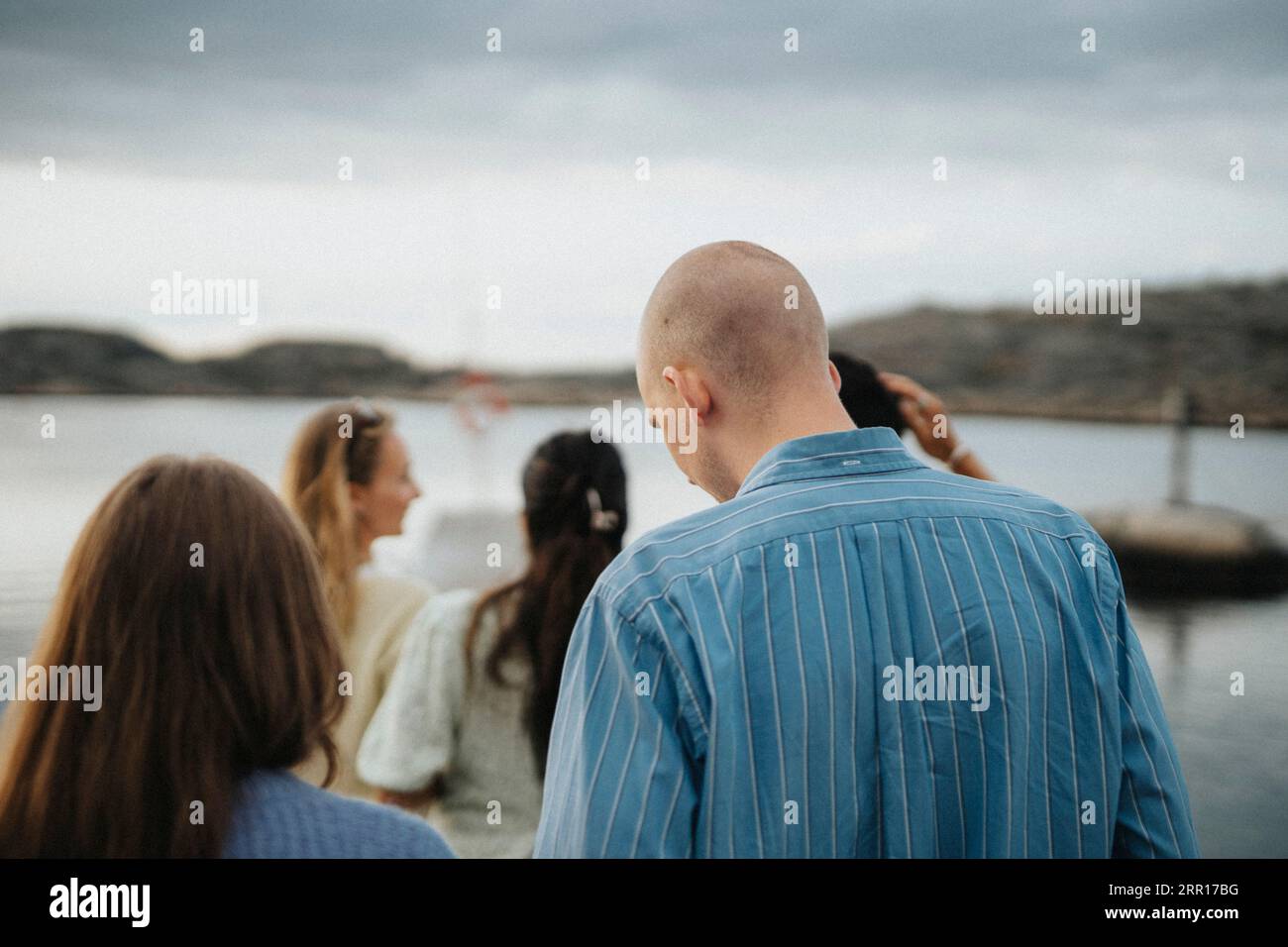 Rear view of man and woman enjoying with friends near lake Stock Photo
