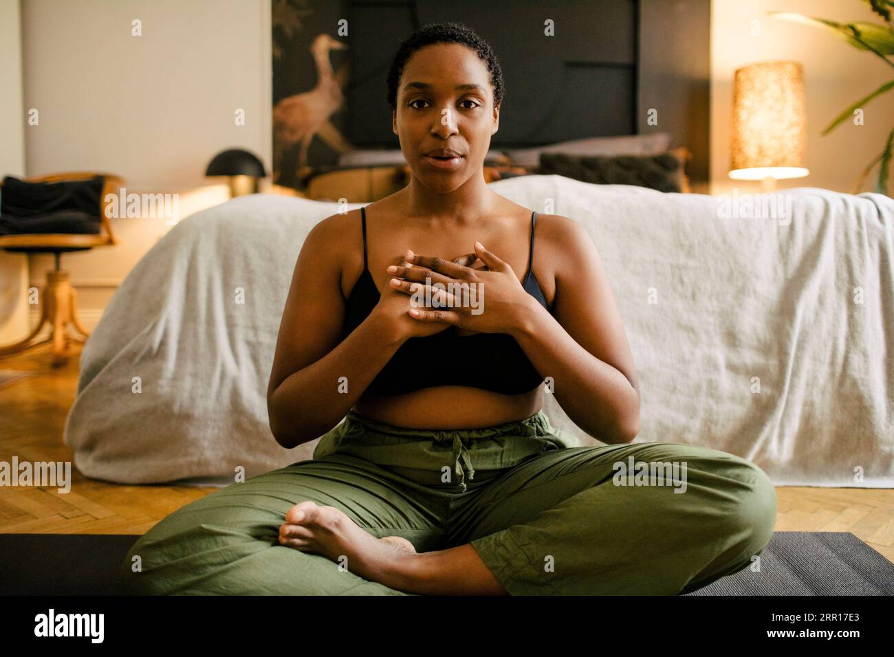Portrait of young woman practicing breathing exercise in bedroom at home Stock Photo