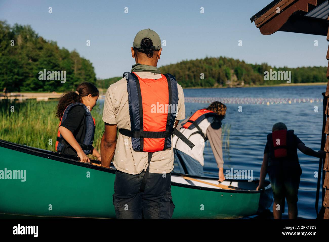 Rear view of male counselor going for kayaking with kids at summer camp Stock Photo