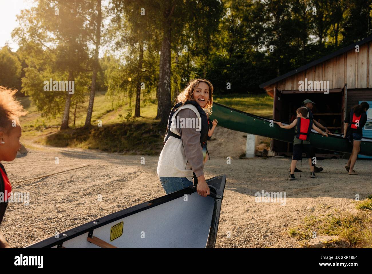 Counselor assisting kids carrying kayak at summer camp Stock Photo