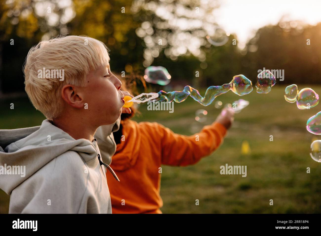 Side view of blond boy blowing bubbles while playing in playground Stock Photo