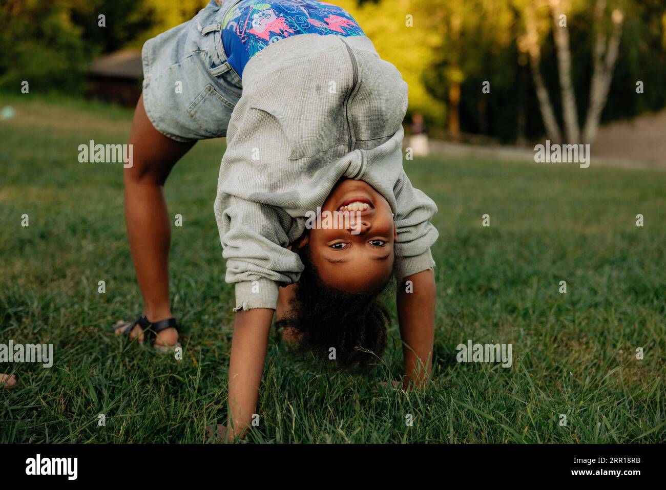 Portrait of smiling girl practicing bridge position on grass in playground Stock Photo