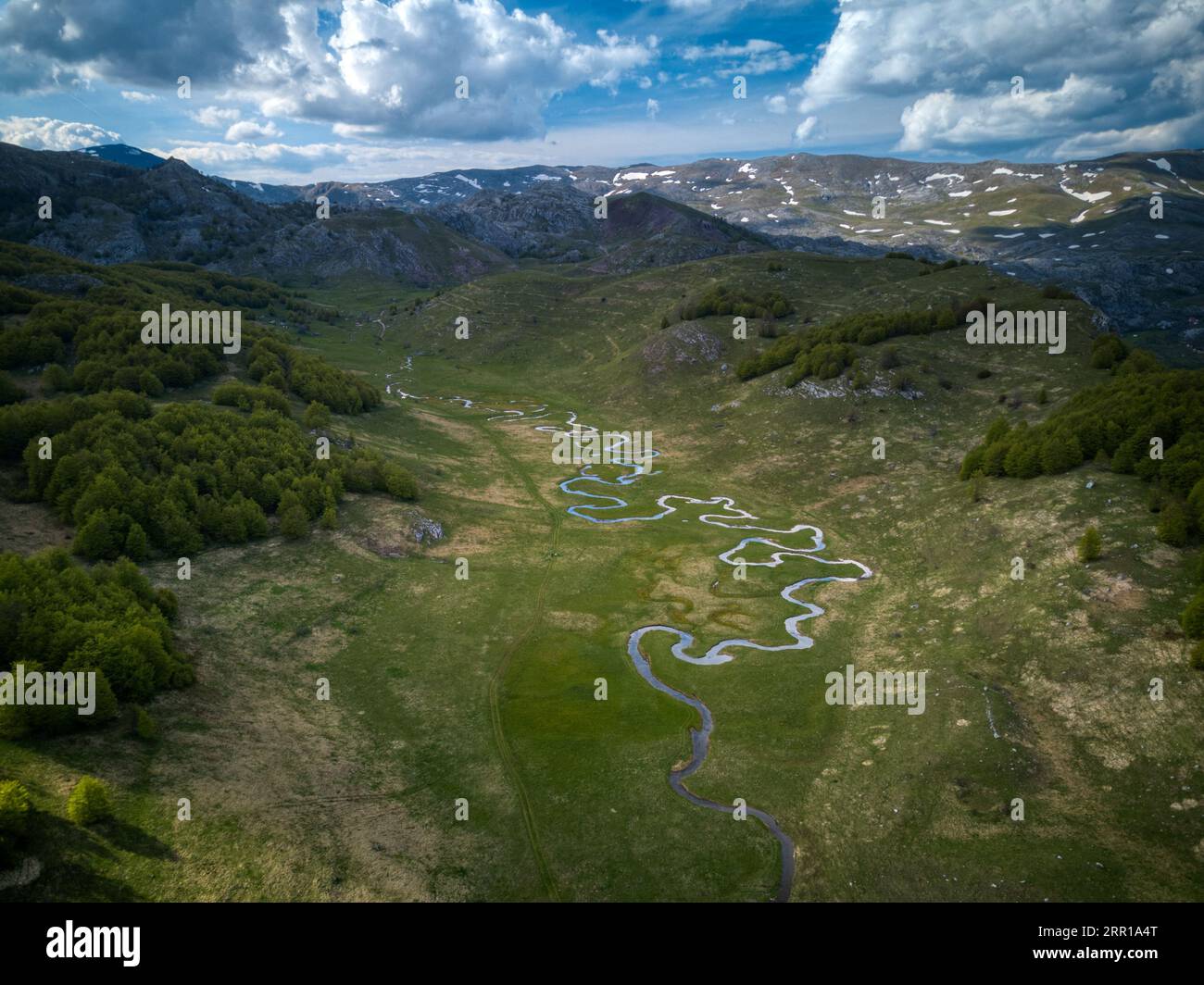 An aerial view of a river flowing through green mountains Stock Photo ...