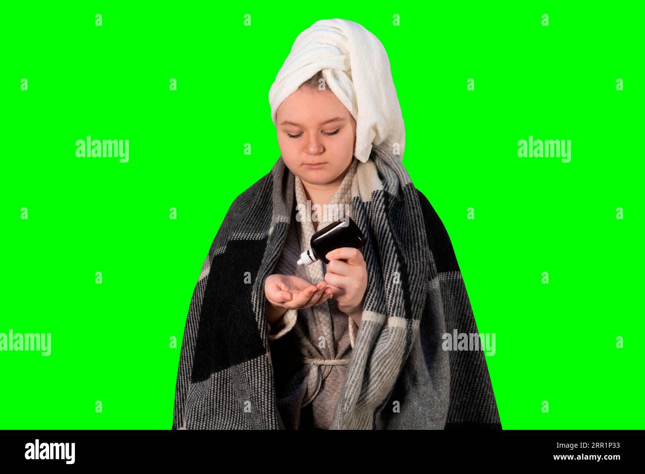 Girl with cold symptoms pours a disinfectant from a bottle onto her hand on a green background (chroma key). Concept of healthcare and home treatment Stock Photo