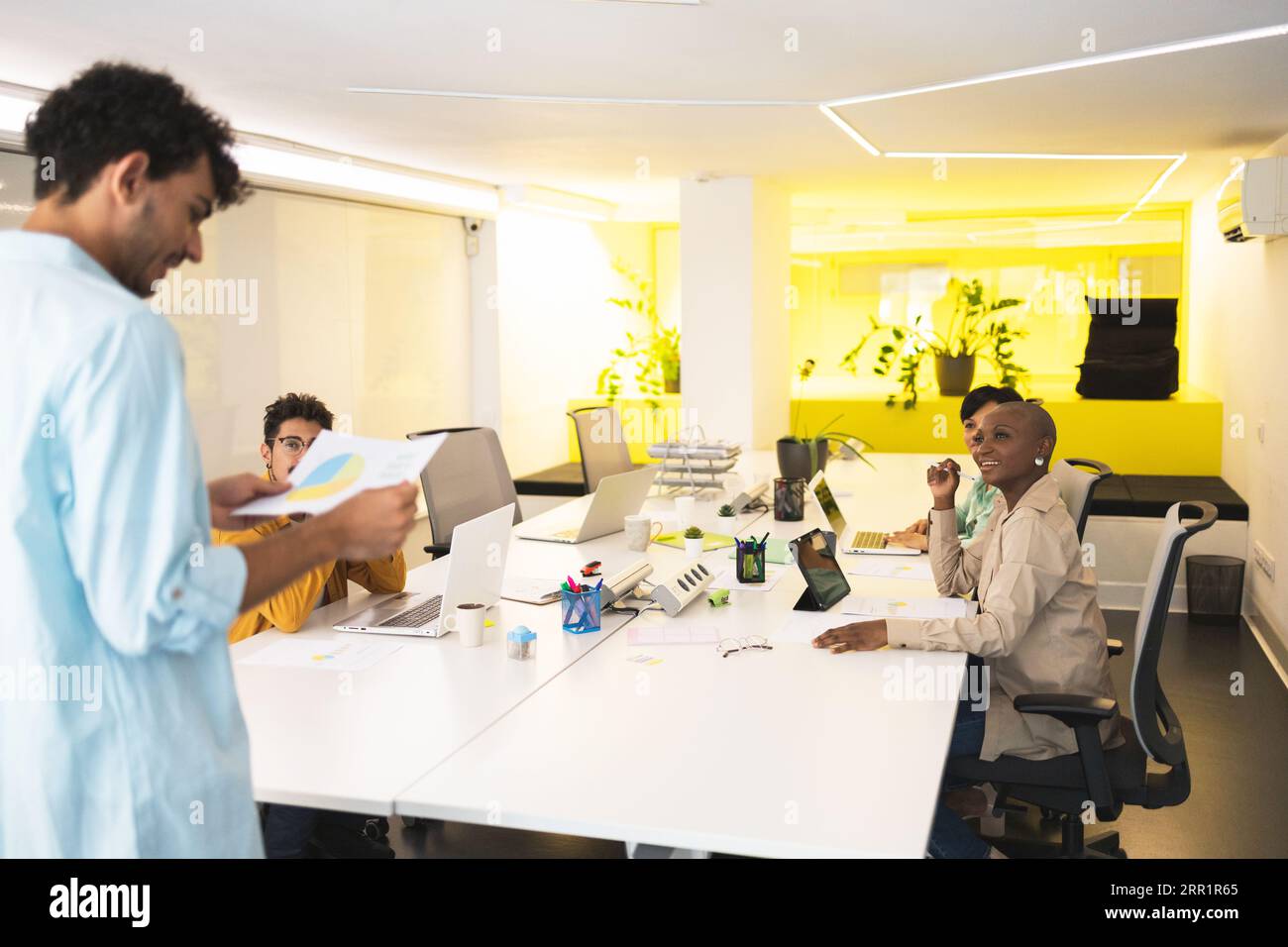 Group of multiracial employees gathering together while working at project at white desk in modern office Stock Photo