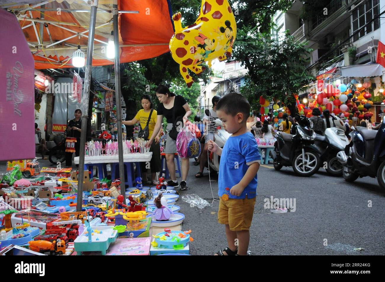 201002 -- HANOI, Oct. 2, 2020 -- A boy selects toys at a stall in an ancient block in Hanoi, Vietnam, Oct. 1, 2020. A traditional Vietnamese Mid-Autumn Festival, celebrated on the eighth lunar month s full moon night, involves the customs of moon contemplating, procession of star and moon-shaped lanterns, lion dance, as well as holding parties with moon cakes and fruits amid the cool weather of autumn. Parents were busy during the harvest, so the holiday after that was a chance to spend time with their children. Over the years, it had been widely recognized as a festive event for kids across t Stock Photo